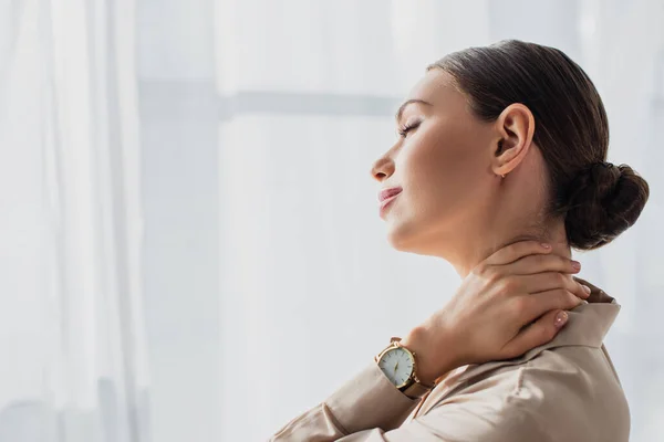 Attractive young businesswoman stretching neck in modern office — Stock Photo