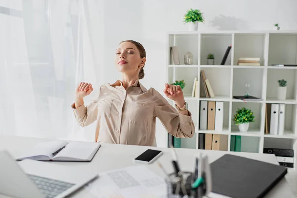 Attractive tired businesswoman stretching in modern office — Stock Photo