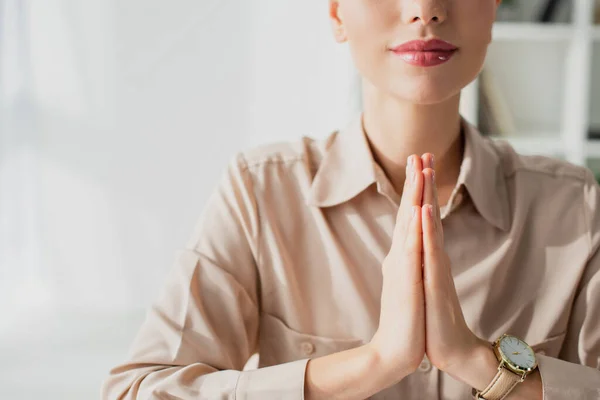 Cropped view of businesswoman meditating with namaste gesture in office — Stock Photo