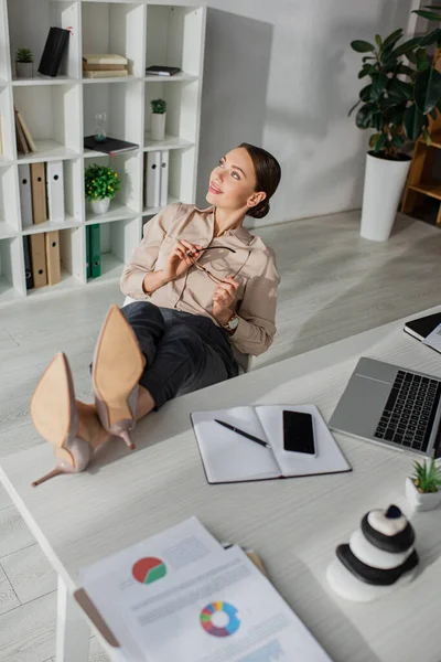 Schöne junge Geschäftsfrau zaudert mit Füßen auf dem Tisch im Büro — Stockfoto