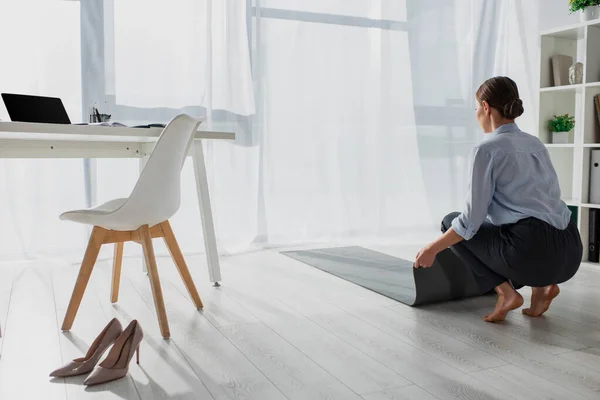 Молодая предпринимательница кладет коврик на пол в офисе — стоковое фото