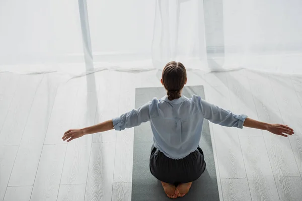 Rückenansicht einer Geschäftsfrau, die im Büro Yoga auf Matte praktiziert — Stockfoto