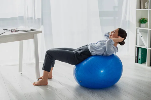 Jovem sorridente empresária fazendo abs em bolas de fitness no escritório — Fotografia de Stock