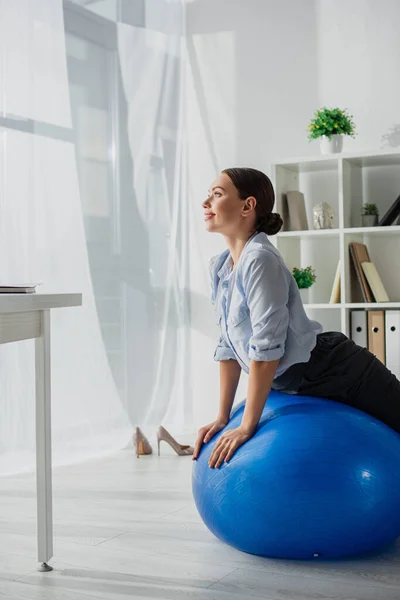 Happy businesswoman exercising on fitness balls in office — Stock Photo