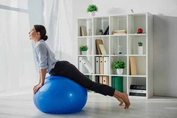 Glückliche Geschäftsfrau dehnt sich im Büro auf Fitnessbällen — Stockfoto