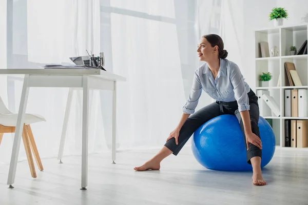 Lächelnde Geschäftsfrau trainiert im Büro auf Fitnessbällen — Stockfoto