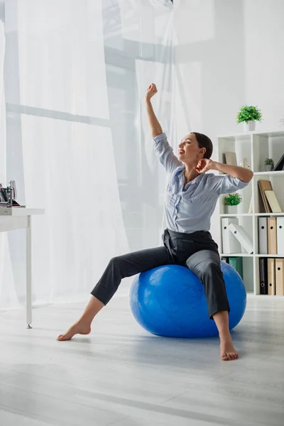 Schöne, glückliche Geschäftsfrau dehnt sich im Büro auf Fitnessbällen — Stockfoto