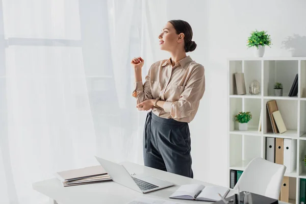 Happy tired businesswoman stretching arms in modern office — Stock Photo