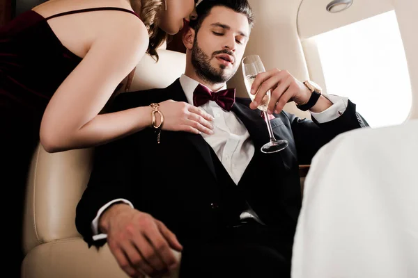 Abgeschnittene Ansicht einer verführerischen Frau, die einen eleganten, selbstbewussten Mann mit einem Glas Champagner berührt — Stockfoto