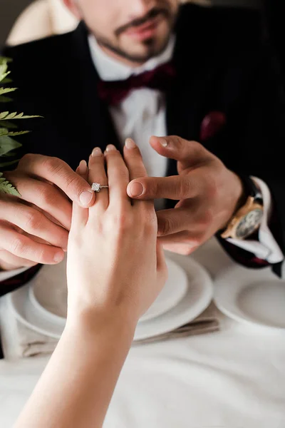 Vue partielle de l'homme mettant l'alliance sur le doigt sur la femme tout en faisant la demande en mariage dans l'avion — Photo de stock