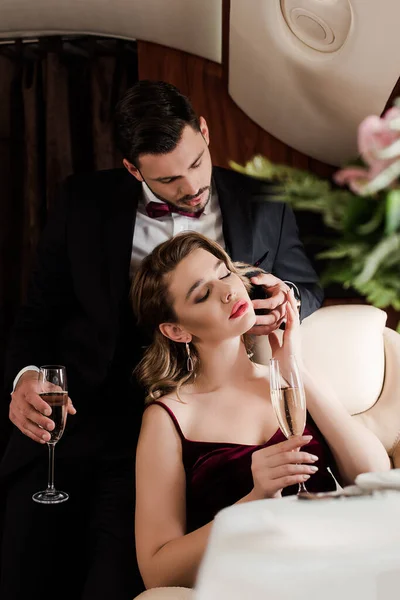 Selective focus of elegant man touching face of attractive woman in plane — Stock Photo