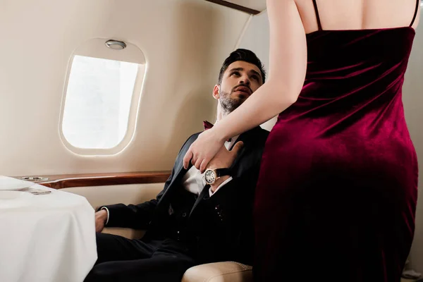 Обрезанный вид элегантной женщины, держащей за руку элегантного мужчину в самолете — стоковое фото