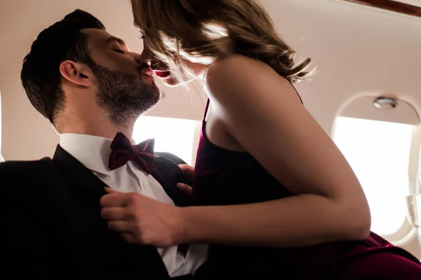 Mulher sensual beijando homem elegante enquanto voa no avião — Fotografia de Stock