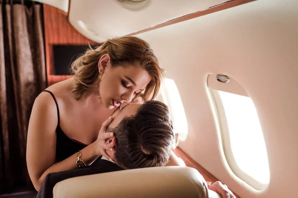 Attraktive, sexy Frau küsst Mann im Flugzeug — Stockfoto