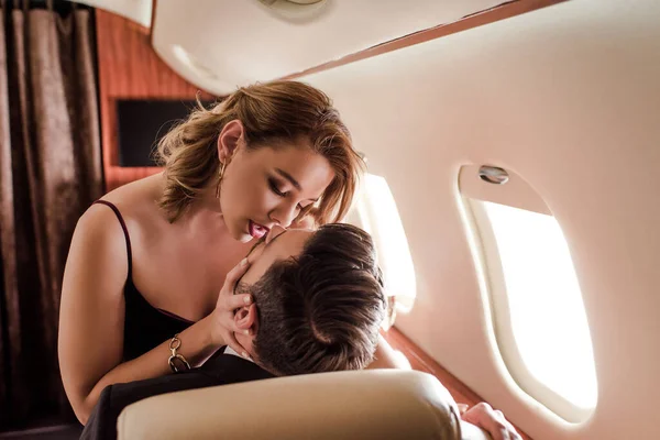 Attractive, sexy woman kissing man in plane — Stock Photo