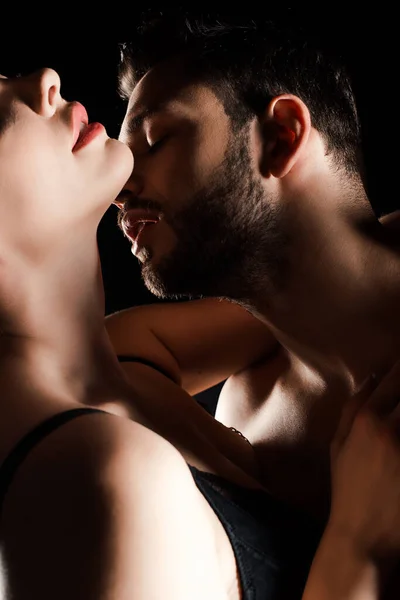 Recortado vista de seductora chica abrazando con sexy hombre aislado en negro - foto de stock
