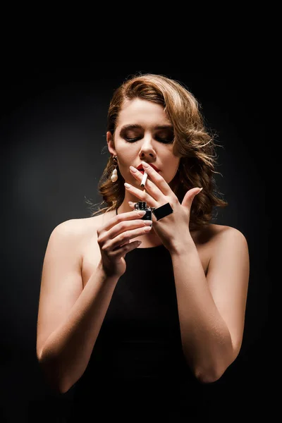Attraktive, elegante Frau zündet sich Zigarette auf schwarzem Hintergrund an — Stockfoto
