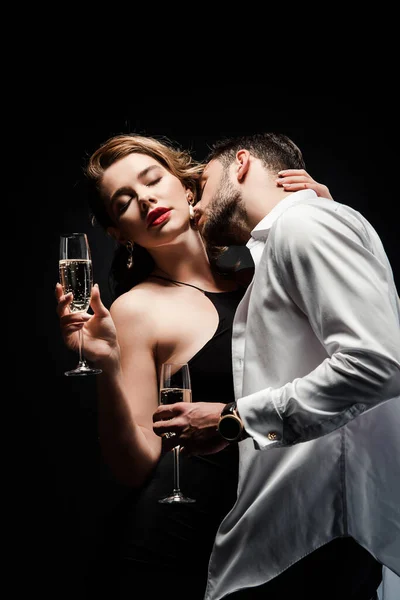 Young man in white unbuttoned shirt kissing sexy, elegant girl isolated on black — Stock Photo