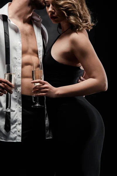 Обрезанный вид сексуального мужчины в расстегнутой рубашке, обнимающего элегантную, соблазнительную девушку, изолированную на черном — стоковое фото
