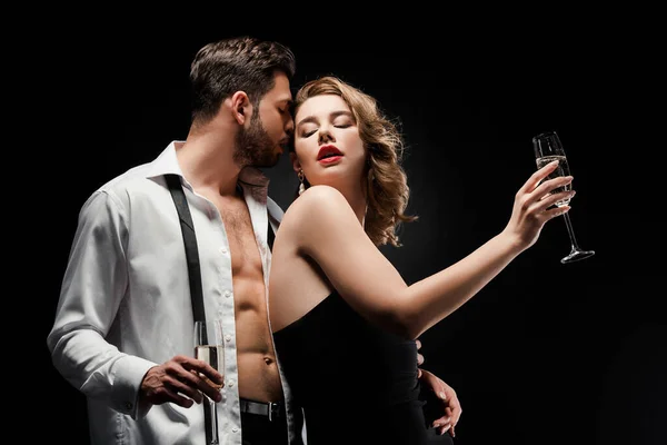 Sexy man in unbuttoned shirt hugging elegant, seductive girl isolated on black — Stock Photo