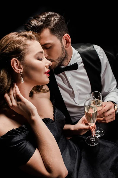 Stylish, seductive woman and elegant man clinking glasses of champagne isolated on black — Stock Photo