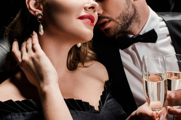 Vista ritagliata di uomo elegante vicino donna sensuale toccare il collo isolato su nero — Foto stock