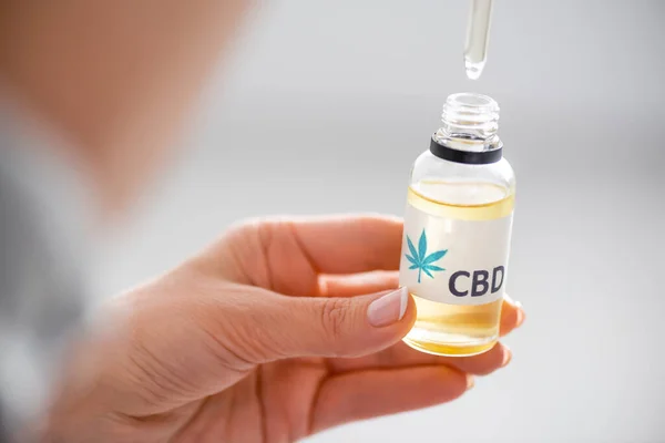 Selective focus of woman holding pipette and bottle with cbd lettering — Stock Photo