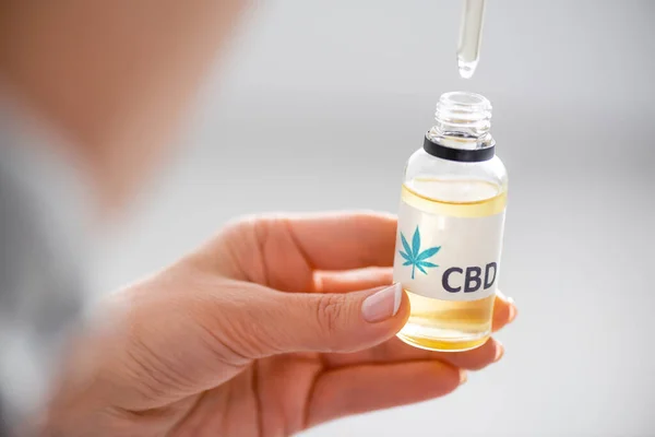 Foyer sélectif de la femme tenant pipette et bouteille avec lettrage cbd — Photo de stock