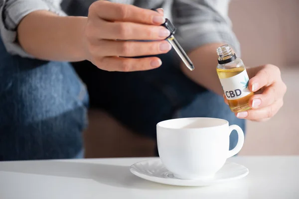 Abgeschnittene Ansicht einer reifen Frau, die cbd in einer Tasse Tee hinzufügt — Stockfoto