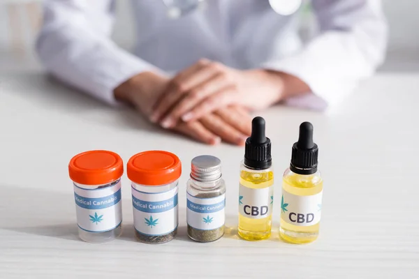 Selective focus of bottles with cbd and medical cannabis lettering near doctor — Stock Photo