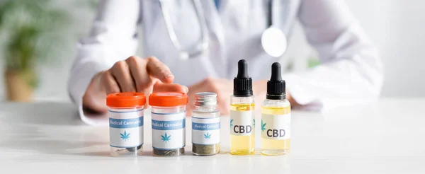 Inyección panorámica del médico señalando con el dedo a la botella con letras de cannabis medicinal - foto de stock