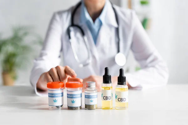 Cropped view of doctor pointing with finger at bottle with medical cannabis lettering — Stock Photo