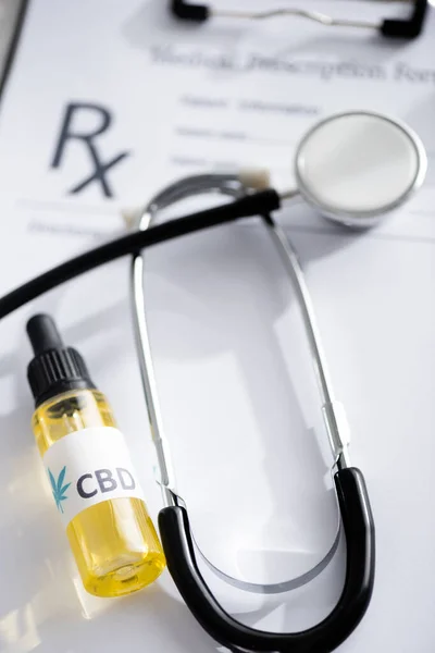 Selective focus of bottle with cbd lettering near stethoscope and clipboard — Stock Photo