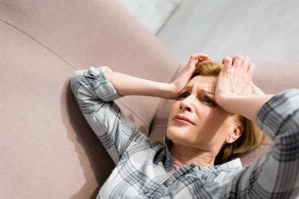 Donna matura che soffre di mal di testa mentre si trova sul divano — Foto stock