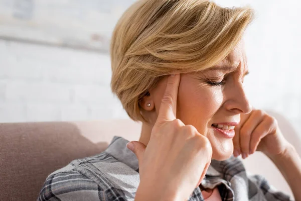 Mature woman with closed eyes suffering from migraine at home — Stock Photo