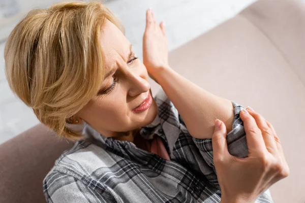 Mature woman suffering from pain in elbow at home — Stock Photo