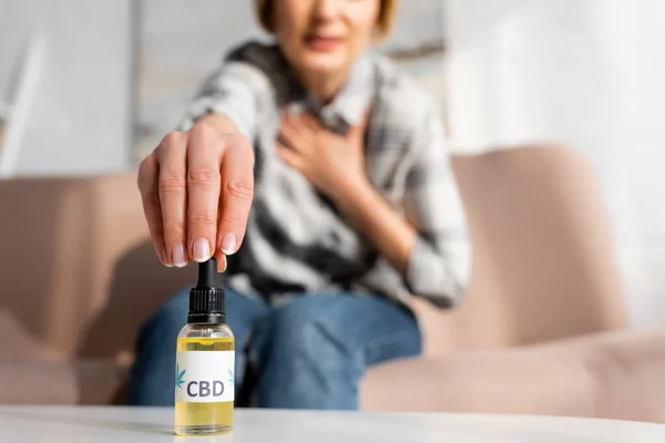 Обрізаний вид зрілої жінки, що бере пляшку з пляшкою Cbd вдома — стокове фото