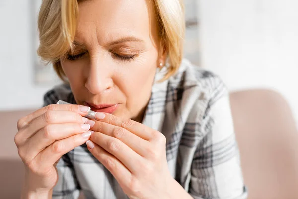 Mature woman with closed eyes blowing on joint with legal marijuana at home — Stock Photo