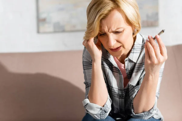 Mature woman with migraine holding joint with weed at home — Stock Photo