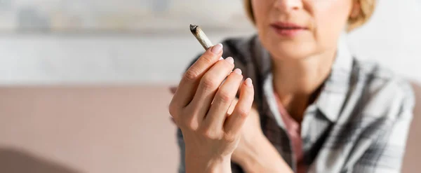 Panoramic shot of mature woman holding joint at home — Stock Photo