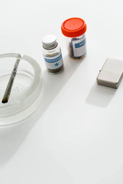 Flaschen mit medizinischem Cannabis nahe Feuerzeug, Aschenbecher und Joint mit legalem Marihuana — Stockfoto