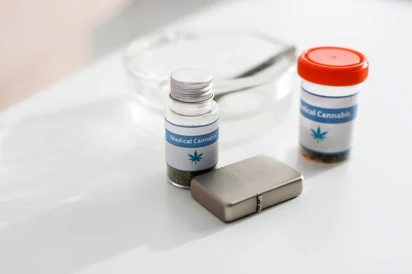 Selective focus of bottles with medical cannabis near lighter, ashtray and joint with legal marijuana — Stock Photo