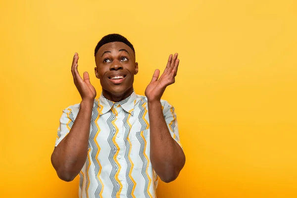 Glücklicher afrikanisch-amerikanischer Mann gestikuliert auf gelbem Hintergrund — Stockfoto