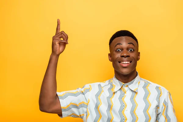 Heureux homme afro-américain pointant avec le doigt vers le haut sur fond jaune — Photo de stock