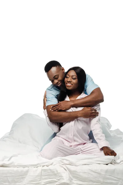 Heureux couple afro-américain étreignant au lit en pyjama isolé sur blanc — Photo de stock