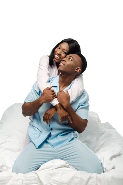 Щаслива афро-американська пара обіймається в ліжку в піжамі ізольована на білому — стокове фото