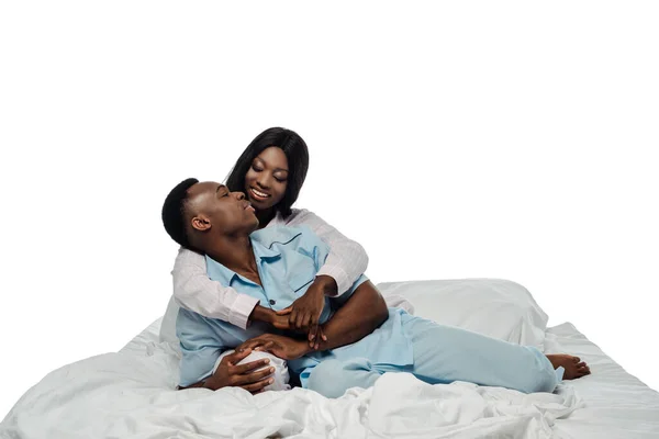 Feliz casal afro-americano abraçando na cama em pijama isolado no branco — Fotografia de Stock