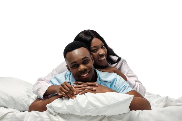 Glücklich afrikanisch-amerikanisches Paar liegt im Bett im Pyjama isoliert auf weiß — Stockfoto