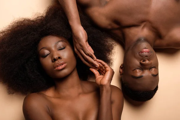 Vista aérea de sexy nu casal afro-americano deitado com os olhos fechados no bege — Fotografia de Stock