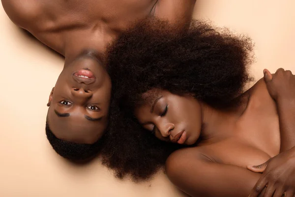 Overhead-Ansicht von sexy nackten afrikanisch-amerikanischen Paar liegend mit geschlossenen Augen auf beige — Stockfoto